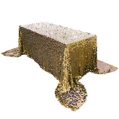 a table covered in gold sequins on top of a white surface with a silver cloth over it