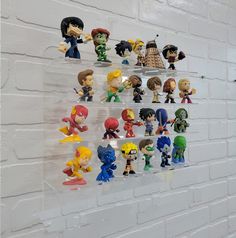 a bunch of figurines are hanging on the wall in front of a white brick wall