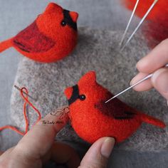 two red birds sitting on top of a rock with needles in their beaks,