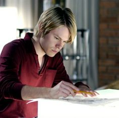 a man sitting at a table working on something