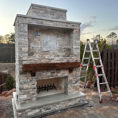 an outdoor fireplace with a ladder next to it