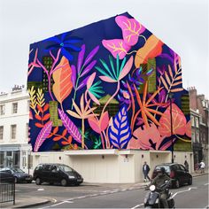 a colorful building with lots of flowers painted on it's side and cars parked in front