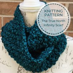 a blue knitted scarf on top of a mannequin torso with text overlay reading knitting pattern the true north infinity scarf