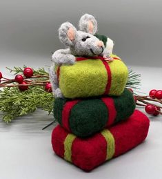 three small stuffed animals are sitting on top of each other, one is green and the other is red