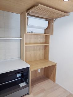 an empty room with some shelves and a small stove in the corner, next to a wall mounted air conditioner