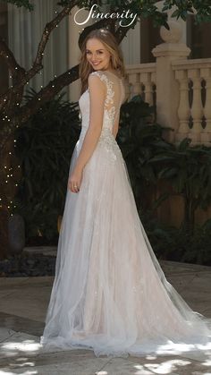 a woman in a wedding dress standing under a tree