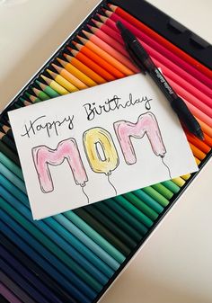 a card that says happy birthday mom with colored crayons and a black marker