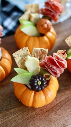 small pumpkins filled with snacks on top of a wooden table