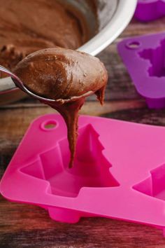 a spoon full of chocolate frosting being lifted from a cake pan with the icing on it