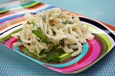 a colorful plate topped with pasta and vegetables on top of a blue table cloth next to a fork