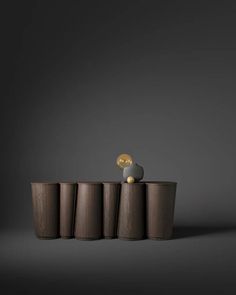 a small figurine is sitting on top of three wooden cylinders in front of a dark background