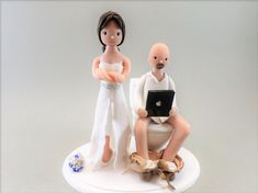 two figurines sitting on top of a toilet with a laptop