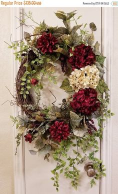 a wreath with red and white flowers hanging on a door