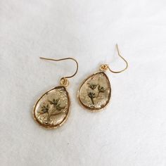 Dainty gold teardrop earrings, made with real pressed flowers preserved in crystal clear resin. These are very light weight! Great gift for nature lovers or anyone who loves minimalist jewelry. See photos for size. Because no two botanicals are identical, your item may not look exactly like the item pictured, however the same quality is guaranteed. Pendant: 24k gold plated brass Earring hooks: 24k gold plated brass GOLD FILLED EARRING HOOKS ADD ON: https://www.etsy.com/listing/840986084/gold-fil Nickel Free Gold Botanical Jewelry, Handmade Gold Earrings For Bridesmaids, Botanical Style Gold Jewelry With Pressed Flowers, Delicate Gold Teardrop Flower Earrings, Handmade Gold Earrings For Bridesmaid Gift, Gold Teardrop Flower Earrings, Teardrop Earrings With Natural Inclusions, Gold Teardrop Jewelry With Birth Flower, Gold Teardrop Jewelry With Birth Flower Detail