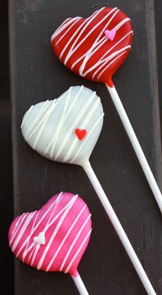 three heart shaped lollipops sitting on top of a black tray next to each other