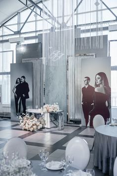 a room filled with tables and chairs covered in white flowers next to two pictures on the wall