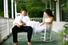 a man and woman are sitting on a porch rocking chair, looking at each other