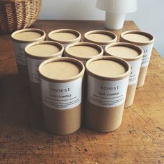 six cups of yogurt sitting on a table next to a basket and vase