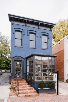 a blue building with stairs leading up to the front door and second story windows on each side