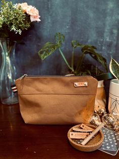 a brown purse sitting on top of a wooden table next to a vase filled with flowers