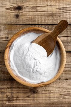 a wooden spoon in a bowl filled with white powder on top of a wooden table