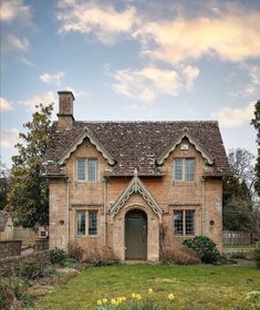 an old brick house with a brown door and windows on the front lawn, surrounded by green grass