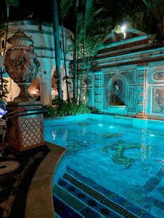 an indoor swimming pool surrounded by palm trees and blue tiles with carvings on the walls