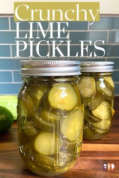 two jars filled with pickles sitting on top of a wooden table