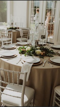 the table is set with white chairs and plates