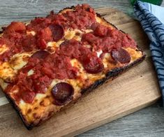 two slices of pepperoni pizza on a blue plate with silverware and utensils