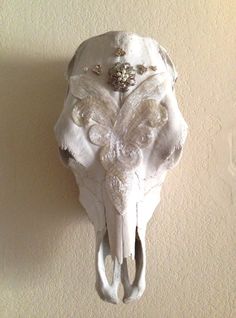 an animal skull mounted to the side of a wall with flowers on it's tusks