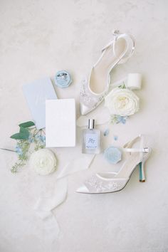 wedding accessories including shoes, ring and bouquet on white background with blue accents for the bride's dress