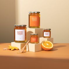 three jars of honey sitting on top of each other next to an orange and a spoon