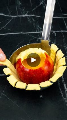 an apple in a bowl with a knife sticking out of the top and another piece of fruit inside it