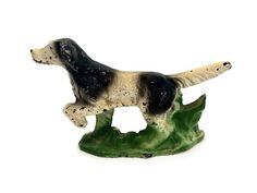 a figurine of a dog standing on top of a green leafy plant