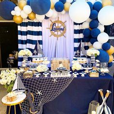 a table topped with lots of desserts and balloons in front of a blue and white backdrop