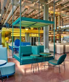 the interior of a restaurant with blue and green chairs, tables, and bar stools