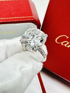 a close up of a diamond ring in a red box with the word cartier on it