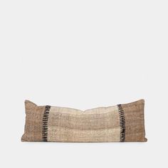 a brown and black striped pillow sitting on top of a white wall