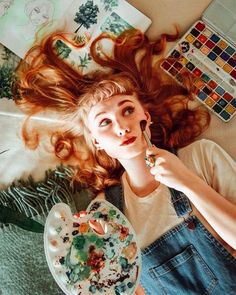 a woman laying on the floor with her hair blowing in the wind while holding a plate