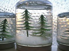 three glass jars with pine trees in them