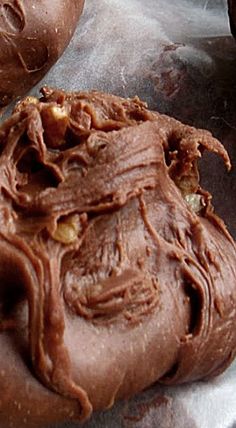 two chocolate doughnuts sitting on top of a piece of tin foil covered in frosting