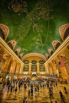 many people are walking around in the building with green ceilings and paintings on the ceiling