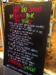 a blackboard with writing on it in front of a store window that says, why you should buy them a book this year?