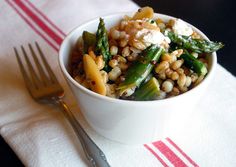 a white bowl filled with food on top of a table next to a fork and knife