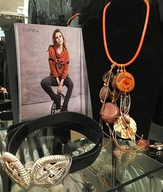 an assortment of jewelry on display in a glass case with a photo of a woman