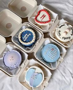 there are nine cupcakes in the box on the bed together, all decorated with different designs