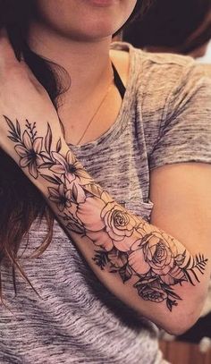 a woman with a flower tattoo on her arm and wrist is looking at the camera