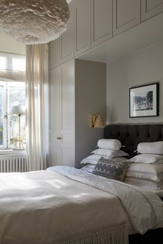 a bed with white linens and pillows in a bedroom next to a large window