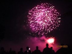 fireworks are lit up in the night sky with people standing around looking at them and taking pictures